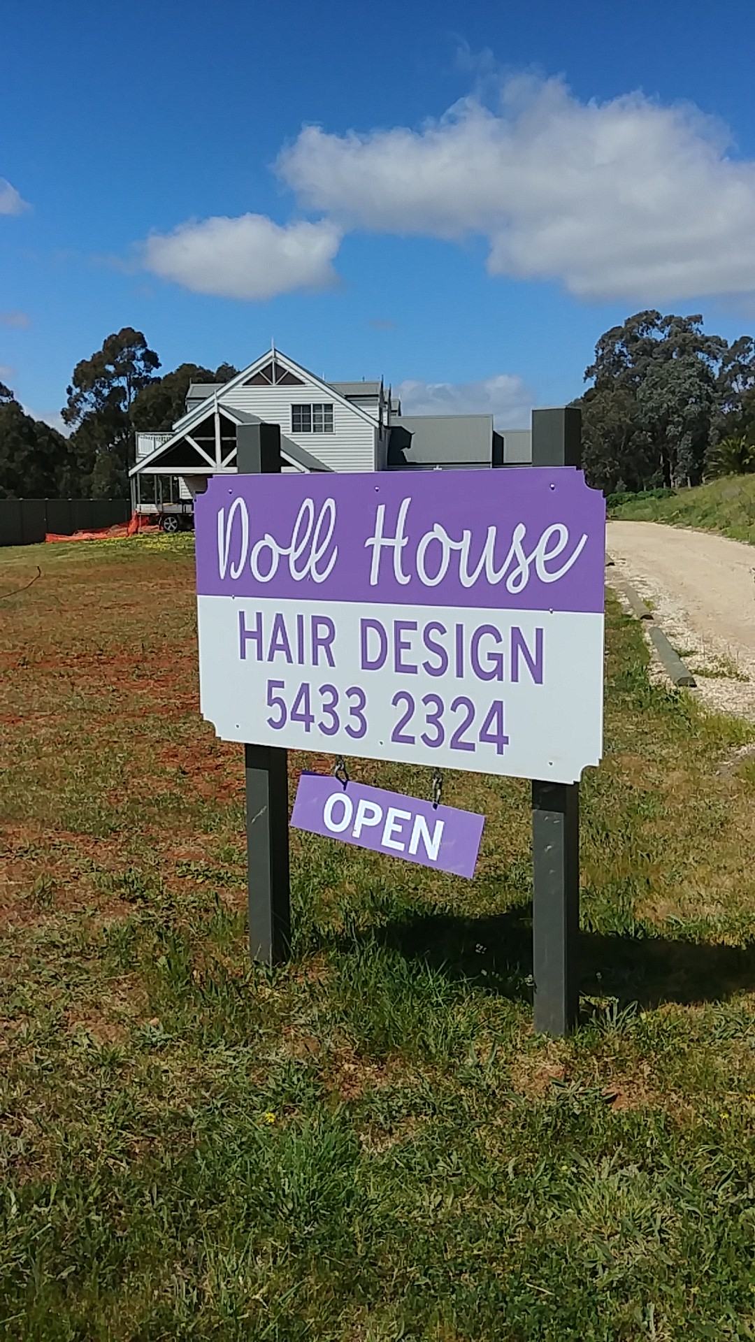 The Doll House Hair Design roadside sign in Heathcote, with an open sign hanging beneath it
