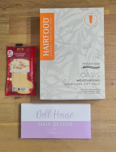 A Doll House Hair Design gift voucher beside a hair care gift pack